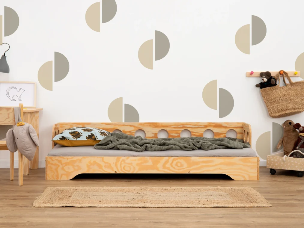 Lit en bois fabriqué en contreplaqué de pin couleur bois verni avec une barrière à ouvertures rondes