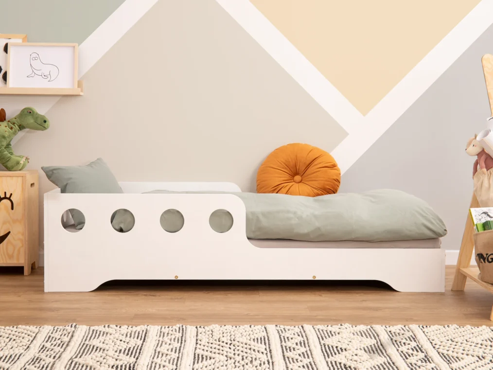 Lit en bois fabriqué en contreplaqué de pin couleur blanc avec une barrière à ouvertures rondes