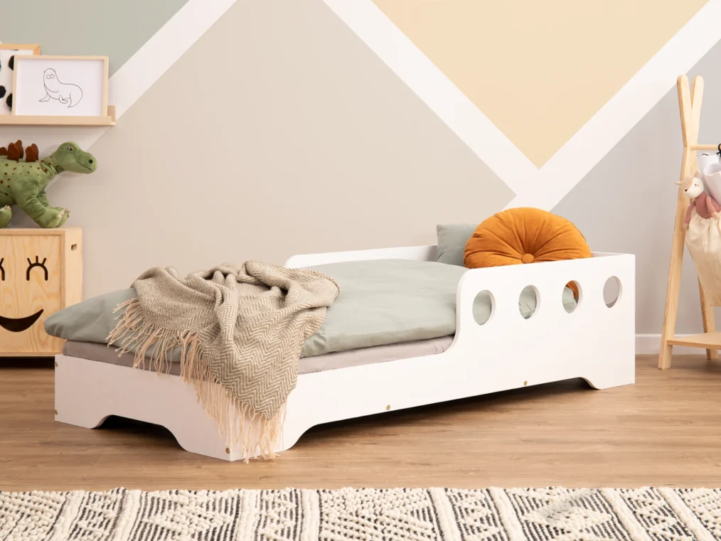 Lit en bois fabriqué en contreplaqué de pin couleur blanc avec une barrière à ouvertures rondes