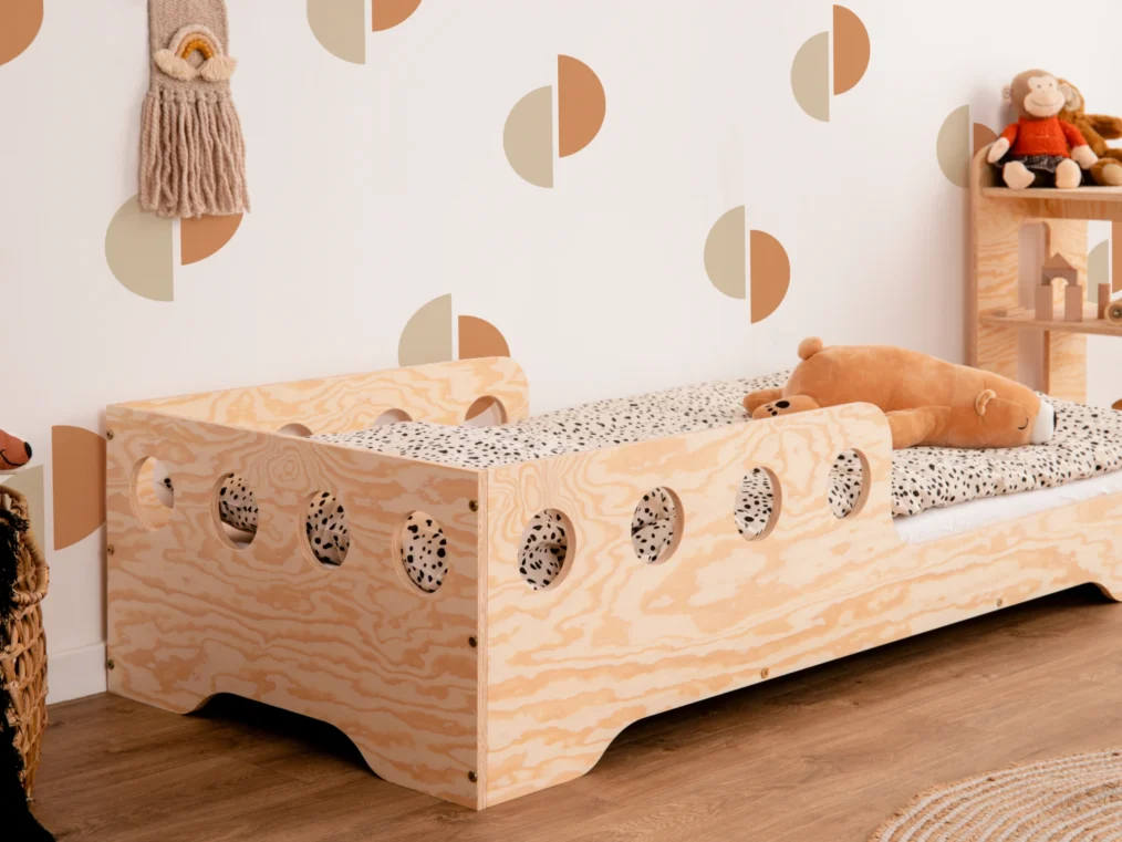 Lit en bois fabriqué en contreplaqué de pin couleur bois naturel avec une barrière à ouvertures rondes