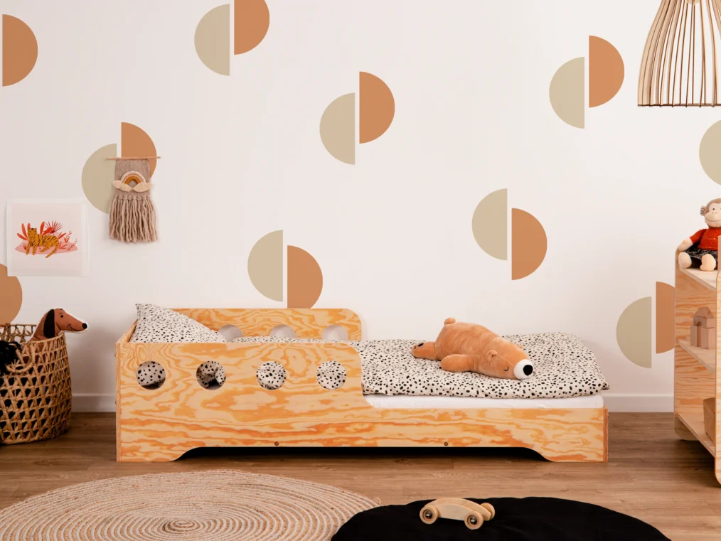 Lit en bois fabriqué en contreplaqué de pin couleur bois verni avec une barrière à ouvertures rondes