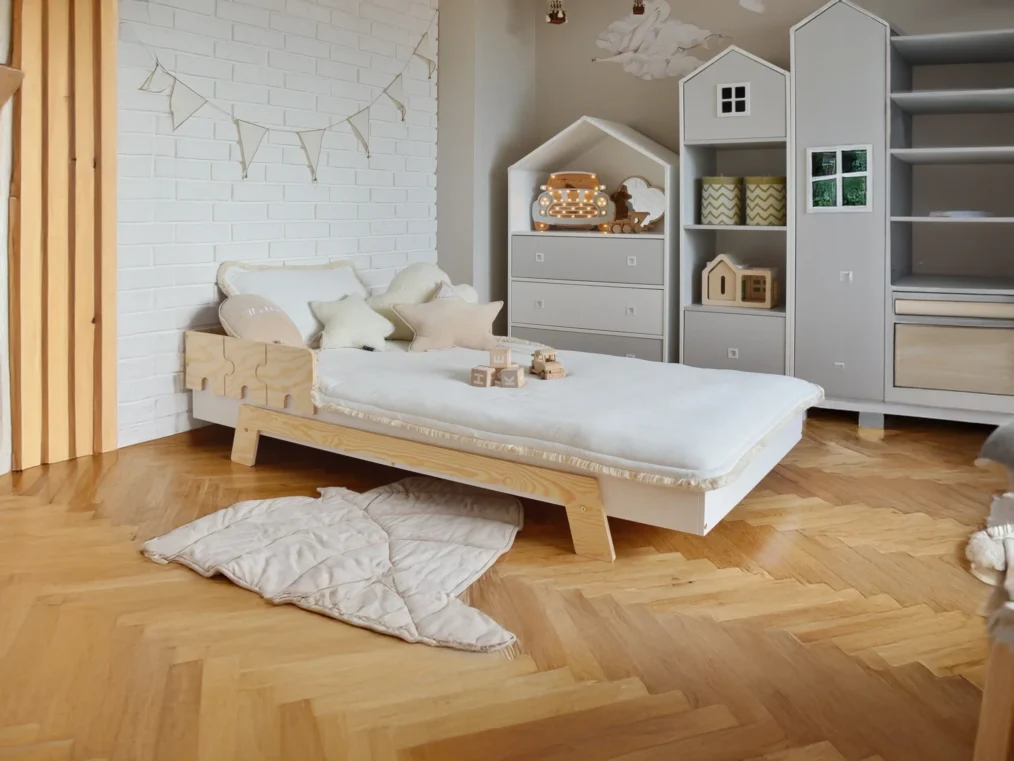 Lit en bois fabriqué en contreplaqué de pin avec une barrière en forme de puzzle dans une chambre d’enfant lumineuse