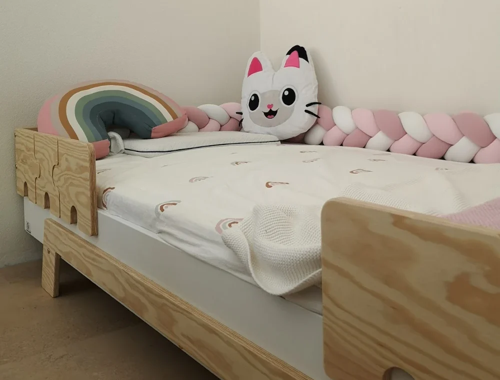 Lit en bois fabriqué en contreplaqué de pin avec des barrières en forme de puzzle dans une chambre d’enfant