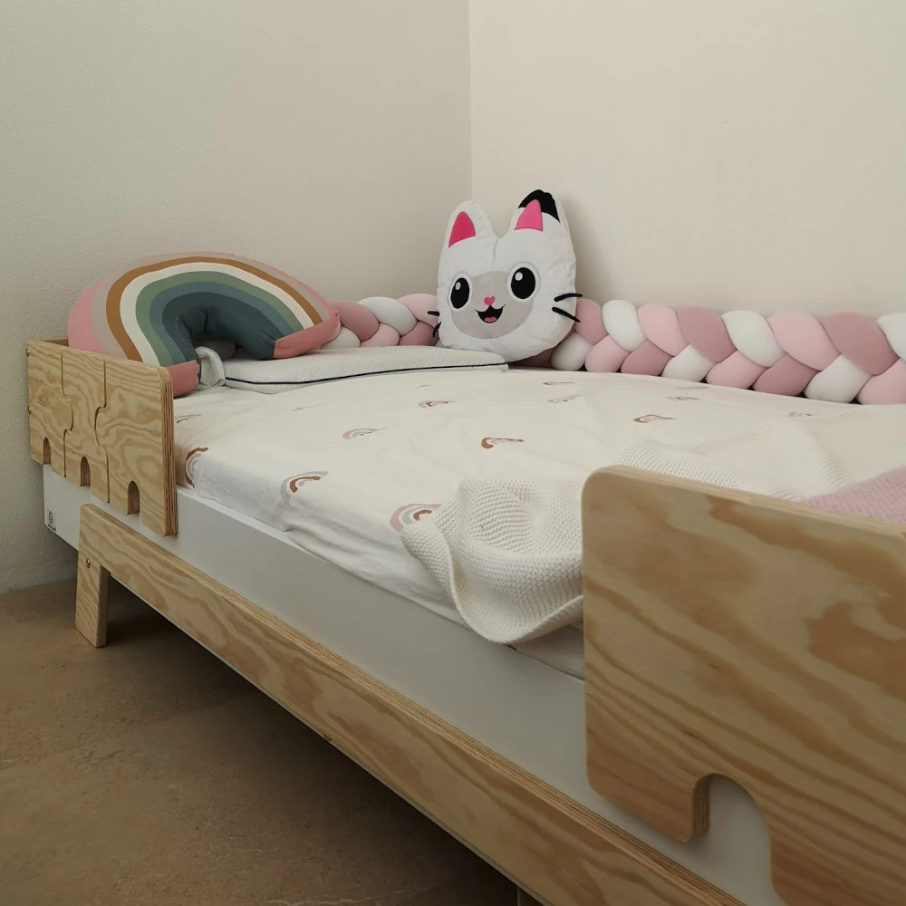 Lit en bois fabriqué en contreplaqué de pin avec des barrières en forme de puzzle dans une chambre d’enfant