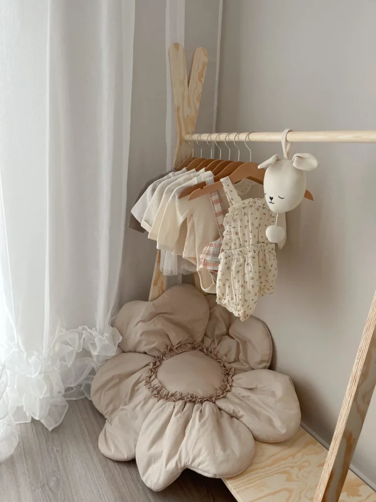 Porte-manteau en bois en forme de tipi avec des vêtements pour enfants suspendus