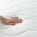 Main pressant la surface d’un matelas pour tester le moelleux