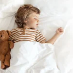 Enfant dormant paisiblement dans un lit, avec un doudou