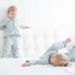 Deux jeunes enfants en pyjama jouent sur un grand lit
