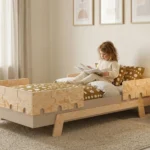 Lit enfant PUZZLE BR1 avec barrières en forme de puzzle en bois naturel - petite fille lisant un livre dans une chambre d'enfant cosy